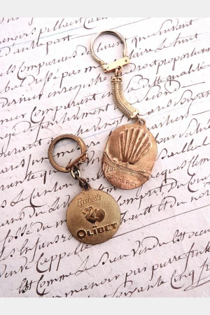 Oude Franse vintage sleutelhanger "Madeleines de la Cloche d'Or"