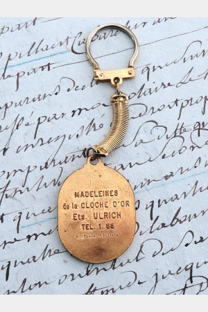 Oude Franse vintage sleutelhanger "Madeleines de la Cloche d'Or"