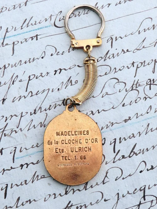 Oude Franse vintage sleutelhanger "Madeleines de la Cloche d'Or"